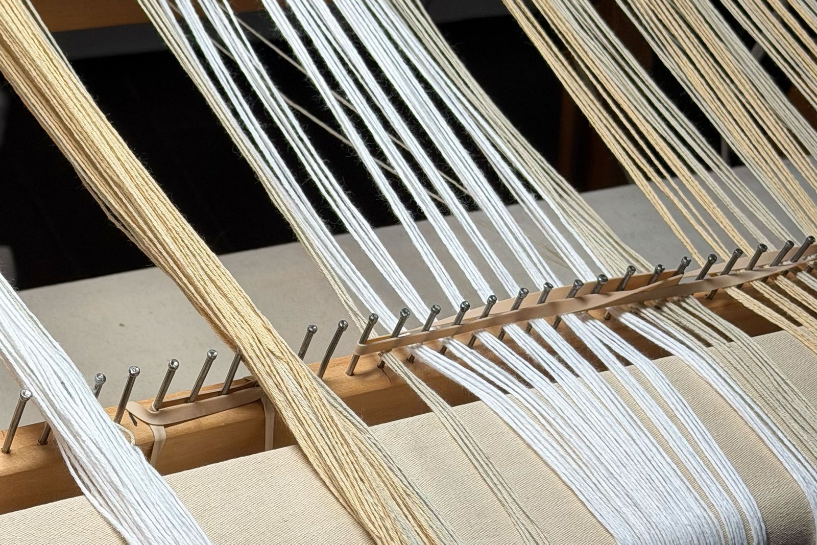 Handwoven cotton warp spread through a raddle on a floor loom during the process of dressing the loom for weaving.