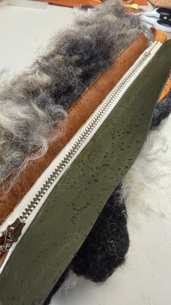 Testing cork and zipper placement against felted wool during a handbag prototype.