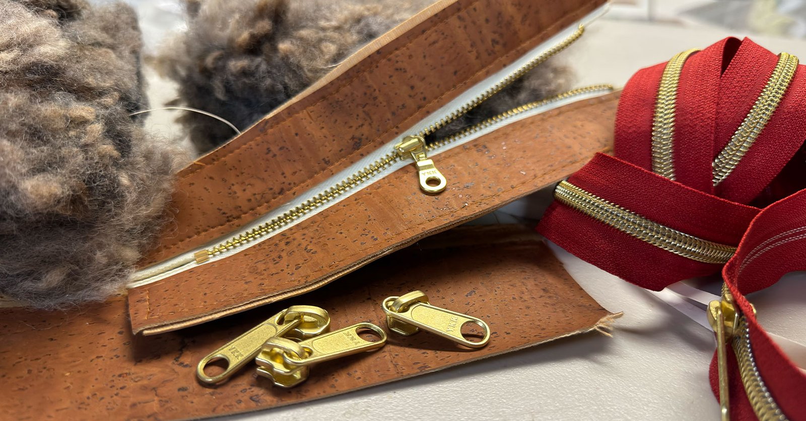 Cork, brass zippers, and raw wool fleece on Karen Borga’s studio worktable during handbag construction.